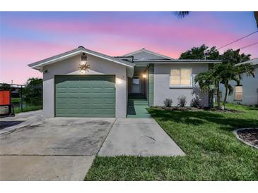 Charming single-story home with a well-manicured lawn, and a one car garage under a vibrant dusk sky at 6603 S Juanita St, Tampa, FL 33616