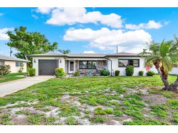 Charming home featuring a well-maintained lawn, stone accents, and attached garage at 7305 Jasmine Blvd, Port Richey, FL 34668