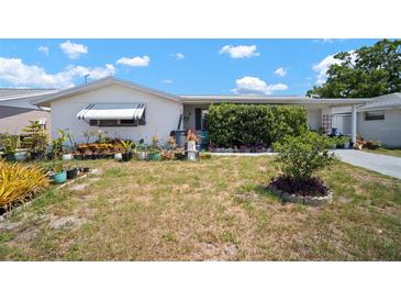 A charming single story home with a white exterior, an awning, and a small well kept front yard at 7415 Ingleside Dr, Port Richey, FL 34668