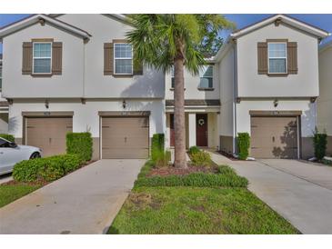 Charming townhome with a well-manicured lawn, brown shutters, and a palm tree in the yard at 17834 Althea Blue Pl, Lutz, FL 33558