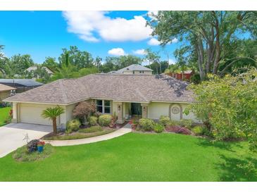 Inviting single-story home featuring a manicured lawn, mature landscaping, and a charming walkway to the entrance at 2806 Fairway View Dr, Valrico, FL 33596