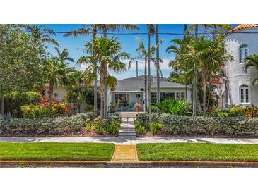 Charming single-story home with lush landscaping, palm trees, and walkway to front door at 301 23Rd Ne Ave, St Petersburg, FL 33704