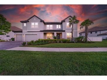 Well-manicured lawn and landscaping surround this home with a three-car garage and neutral-toned exterior paint at 33075 Kateland Dr, Wesley Chapel, FL 33545