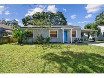 Charming single-story home featuring a bright blue door, covered parking, and a well-manicured lawn at 4009 S Renellie Dr, Tampa, FL 33611