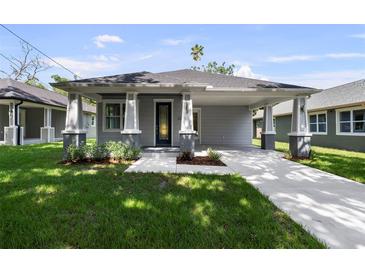 Charming single-story home with a well-manicured lawn, gray siding, and inviting front porch at 5705 N 20Th St, Tampa, FL 33610