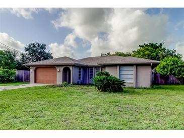 Single-story home featuring an attached garage and a well-maintained lawn at 8330 Lafitte Dr, Hudson, FL 34667