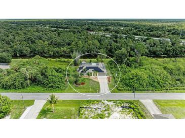 Aerial view of home surrounded by lush greenery and mature trees at 1857 N San Mateo Dr, North Port, FL 34288