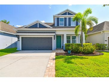 Charming two-story home features a dark gray garage, lush landscaping, and a pop of color on the front door at 11307 Quiet Forest Dr, Tampa, FL 33635