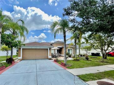 Charming single-story home featuring a well-manicured lawn, complemented by lush tropical landscaping and a two car garage at 3501 Pine Top Dr, Valrico, FL 33594