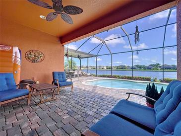 Covered patio featuring brick pavers, comfortable seating, ceiling fan and view of the pool and lake at 11614 Ashton Field Ave, Riverview, FL 33579