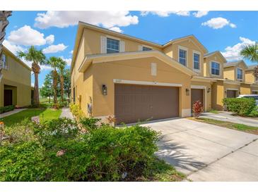 Inviting townhome featuring a two-car garage, manicured landscaping, and a warm, neutral color palette at 2022 Hawks View Dr, Ruskin, FL 33570
