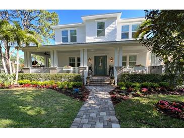 Charming two-story home featuring a welcoming front porch and professionally landscaped yard with colorful flowers at 4423 W Kensington Ave, Tampa, FL 33629