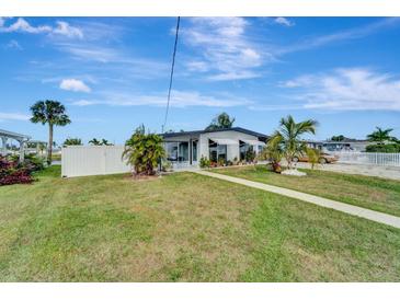Charming single-story home with a well-manicured lawn, modern windows, and a white fence in a waterfront neighborhood at 551 Lindley Ter, Port Charlotte, FL 33952