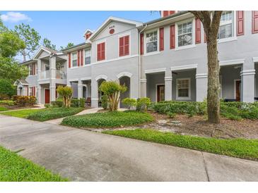 Charming townhome featuring a well-maintained gray exterior, red shutters, and lush landscaping at 9418 W Park Village Dr # 105, Tampa, FL 33626