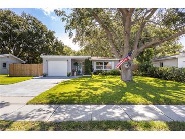 Charming single-story home with a lush front yard and mature tree, American flag and inviting curb appeal at 10095 Oakhurst Rd, Seminole, FL 33776