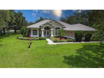 Charming one-story home with well-manicured lawn, mature trees, and elegant architectural details at 13807 Eagles Rock Ct, Hudson, FL 34667