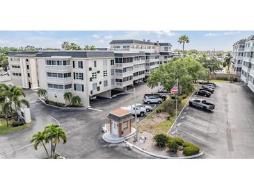 An exterior view of the condo complex showing multi-level buildings, parking, a guard house, and landscaping at 147 Bluff View Dr # 105, Belleair Bluffs, FL 33770