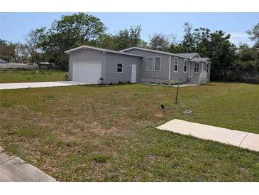 Well-maintained single-Gathering home featuring a grey facade, attached garage, and front lawn at 15591 Charmwood Dr, Hudson, FL 34667