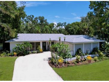 Charming single-story home with a well-manicured front yard and a winding driveway at 1861 Royal Oak E Pl, Dunedin, FL 34698