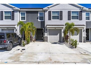 Charming two-story townhome featuring a two-car driveway, one car garage, and tropical landscaping at 2801 Midnight Pearl Dr, Sarasota, FL 34240