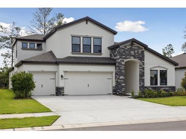 Beautiful two-story home featuring a three car garage and stone archway over the entryway at 3458 Yellow Leaf Cir, Spring Hill, FL 34609