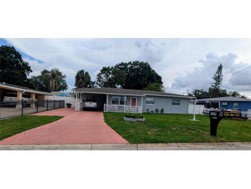 Charming single-story home featuring a covered parking, a well-maintained lawn, and a cozy front porch at 7416 Manchester Ln, Tampa, FL 33619