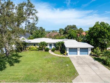Charming single-story home with a well-manicured lawn, lush landscaping, and a two-car garage at 120 Crestwood Ln, Largo, FL 33770