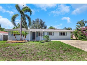 Charming single-story home featuring a well-maintained lawn, palm trees, and a covered entryway at 1420 Temple St, Clearwater, FL 33756
