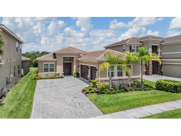 Beautiful single-Gathering home with a paver driveway, lush landscaping, and a two-car garage at 3197 Acacia Bay Ave, Wesley Chapel, FL 33543