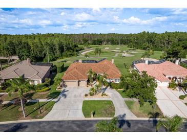 Stunning aerial view of single-story home with tile roof, golf course views and mature landscaping at 3337 Crescent Oaks Blvd, Tarpon Springs, FL 34688