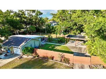 Aerial view of a well-maintained home with a fenced yard, lush greenery, and a covered parking area at 4901 Taylor N St, St Petersburg, FL 33714