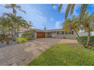 Charming single-story home featuring a spacious brick driveway, lush lawn, and mature tropical landscaping at 735 123Rd Ave, Treasure Island, FL 33706