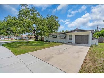 Charming single-story home featuring a well-manicured lawn and a long driveway leading to the attached garage at 8501 56Th N St, Pinellas Park, FL 33781