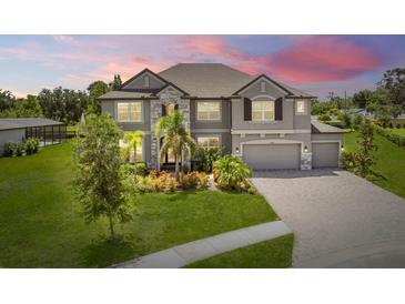 Beautiful two-story home featuring manicured lawn, stone accents, three-car garage, and long driveway at 9508 Pyrenees Pl, Seffner, FL 33584