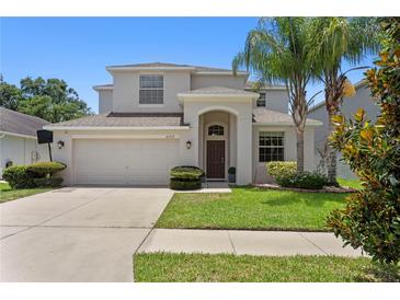 Charming two-story home features a well-manicured lawn, two-car garage and mature palm tree at 10216 Summer Azure Dr, Riverview, FL 33578