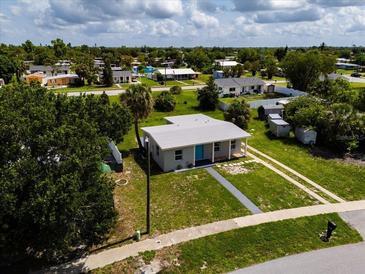 Inviting home featuring a gray exterior, a blue front door, and a spacious lawn at 21536 Holdern Ave, Port Charlotte, FL 33952