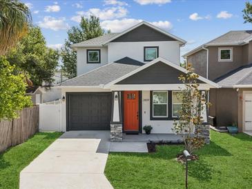Charming two-story home with a well-manicured lawn and inviting orange front door at 2809 N 21St St, Tampa, FL 33605