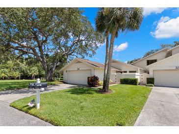 Inviting single-story home featuring a well-maintained lawn, mature trees, and attached garage at 440 Lakeview Dr # 34, Palm Harbor, FL 34683