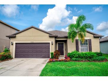 Charming single-story home featuring a well-manicured lawn, lovely flower beds, and a two-car garage at 5003 Wabash Pl, Riverview, FL 33578