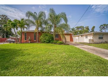 Charming home with a large grassy front yard, palm trees, and a driveway leading to a garage at 51 Cypress Dr, Palm Harbor, FL 34684
