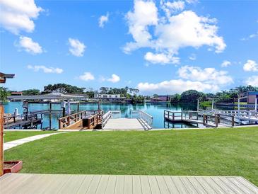 Picturesque backyard features a lush lawn, waterside dock, and beautiful water views on a sunny day at 599 Westwinds Dr # 9, Palm Harbor, FL 34683