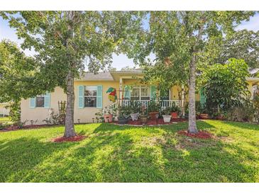Charming home with a well-manicured front yard, featuring lush green grass and mature trees at 630 Mac Crillus Rd, Largo, FL 33770