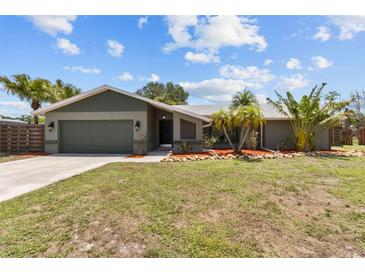 Charming single-story home featuring a well-maintained lawn, mature tropical landscaping, and a two-car garage at 6921 8Th Street E Ct, Sarasota, FL 34243