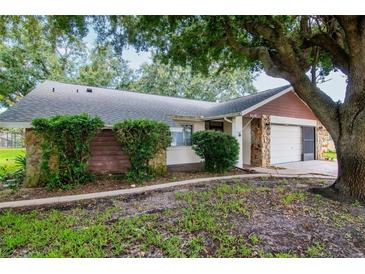Charming single-story home showcasing stone and wood accents plus lush landscaping enhancing its curb appeal at 8626 Woodbridge Dr, New Port Richey, FL 34655