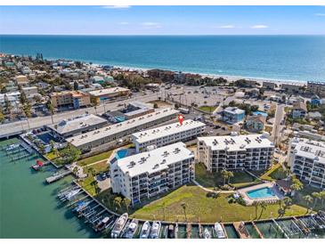 Breathtaking aerial view of waterfront condos, marina, and sandy beach with turquoise ocean waters at 9755 Harrell Ave # 101, Treasure Island, FL 33706