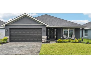 Charming one-story home with a paved driveway, manicured lawn, and a two-car garage in a modern color scheme at 12937 Ogden Glade Rd, Dade City, FL 33525