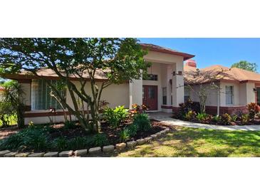Inviting single-story home with mature landscaping and a charming red door at 16502 Windsor Park Dr, Lutz, FL 33549