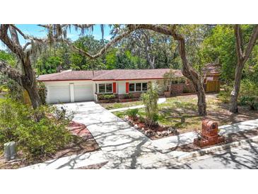 Charming single-story home featuring a red brick facade, white exterior, and manicured landscaping at 327 Sunnyside Rd, Temple Terrace, FL 33617