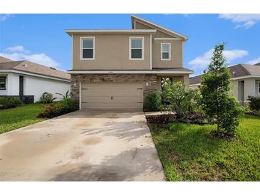 Two-story home with a tan exterior, stone accents, a two-car garage and landscaped front yard at 3528 Maple Grove Way, Plant City, FL 33565