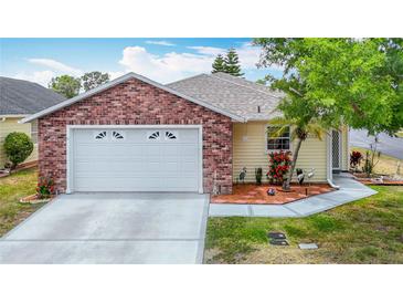 Charming single-story home showcasing a brick facade, manicured landscaping, and a two-car garage at 5755 Yorkshire Dr, Zephyrhills, FL 33542